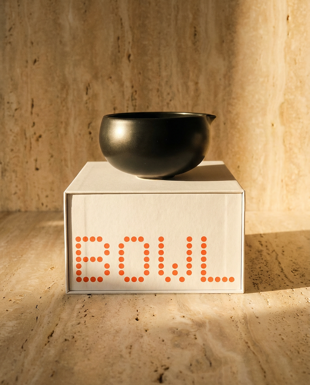 Uchi Bowl, ceramic matcha bowl in matte black, on top of packaging with a travertine backgroud