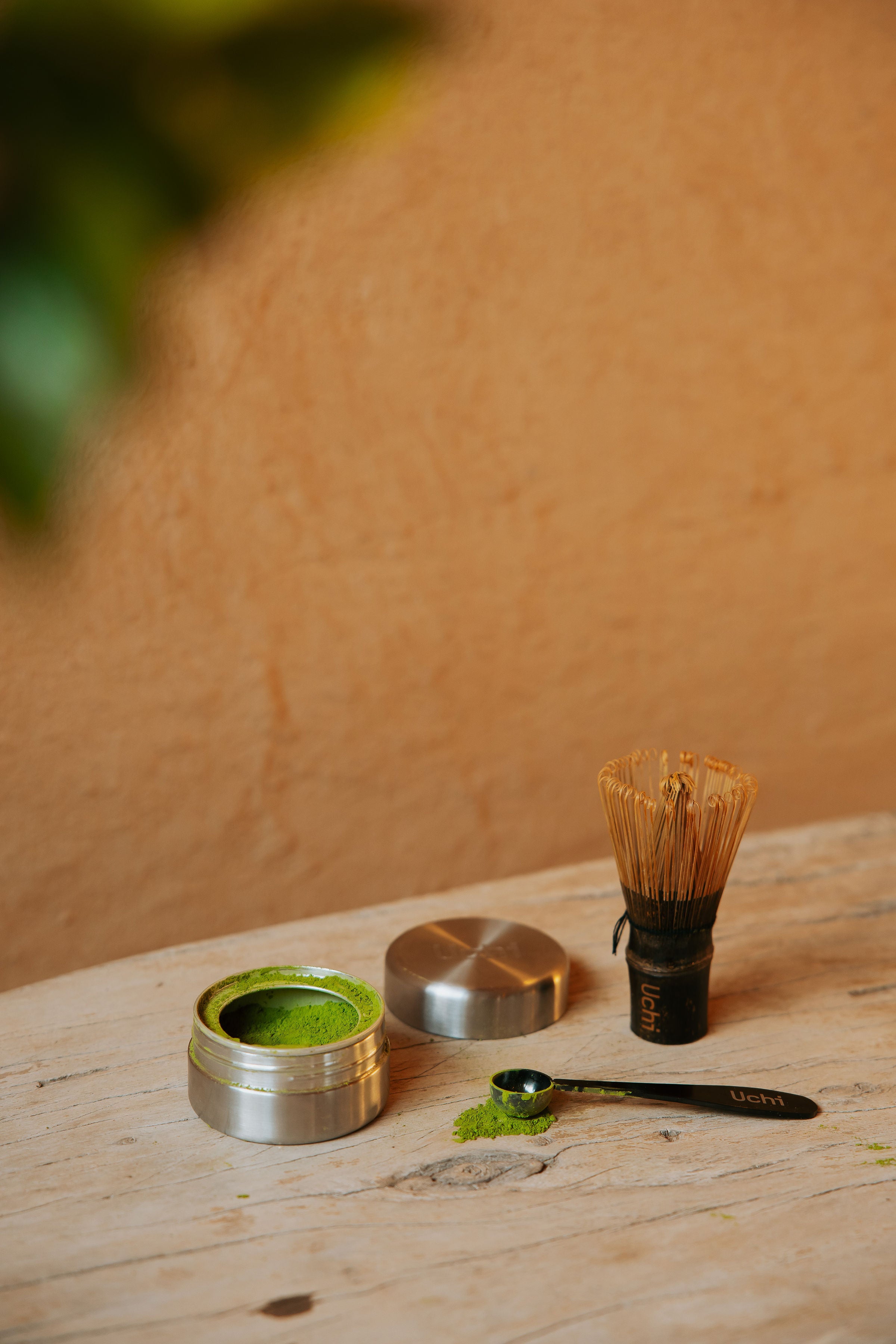 Uchi Pod close-up showing matcha inside. Matcha refill pod containing 40g of ceremonial grade matcha. Dark bamboo handcut matcha whisk and measure spoon